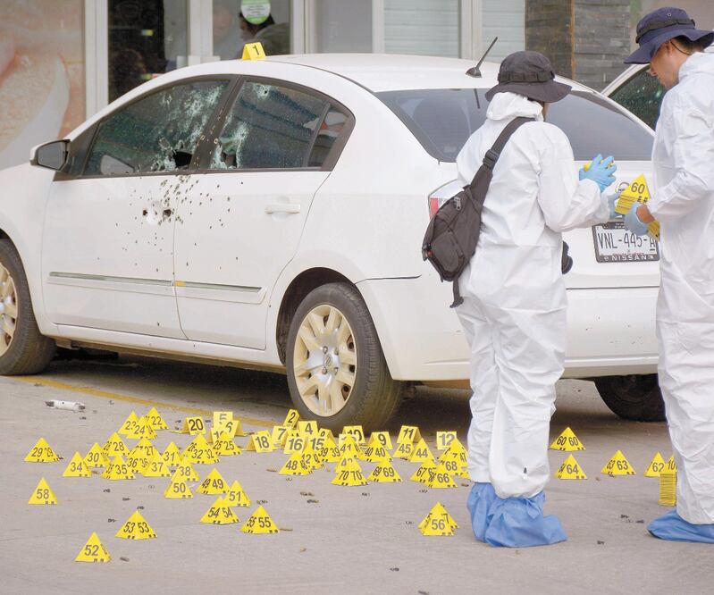 Peritos inspeccionaron el interior del auto en el que se encontraba el oficial Eduardo “N”, y en las inmediaciones del ataque localizaron más de 150 casquillos percutidos de rifles automáticos. JUAN CARLOS CRUZ. CUARTOSCURO 