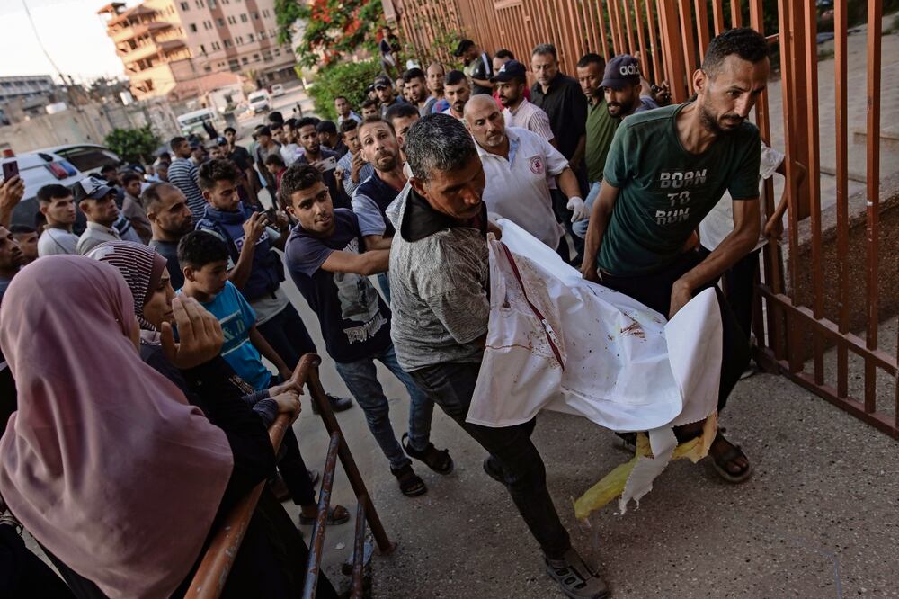 Familias palestinas, con los cuerpos de sus familiares que murieron en un ataque militar, en Gaza. Foto: de HAITHAM IMAD. EFE