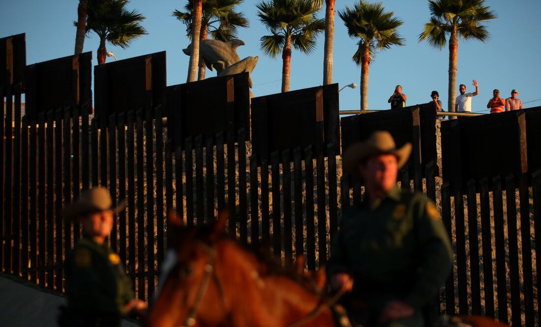 People in Mexico wave at U.S. Border Patrol agents on horseback patrolling the U.S.-Mexico border fence near San Diego, California, U.S., November 10, 2016. REUTERS/Mike Blake/File Photo