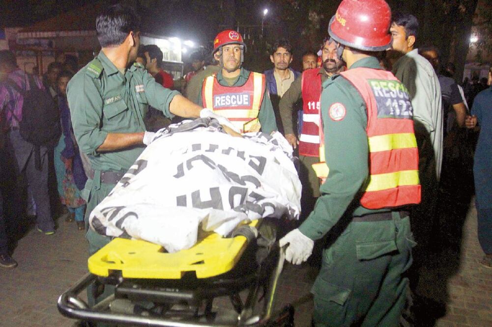 Rescatistas cargan un cuerpo en el parque donde ocurrió ayer un atentado suicida en Lahore, Paquistán (MOHSIN RAZA. REUTERS)
