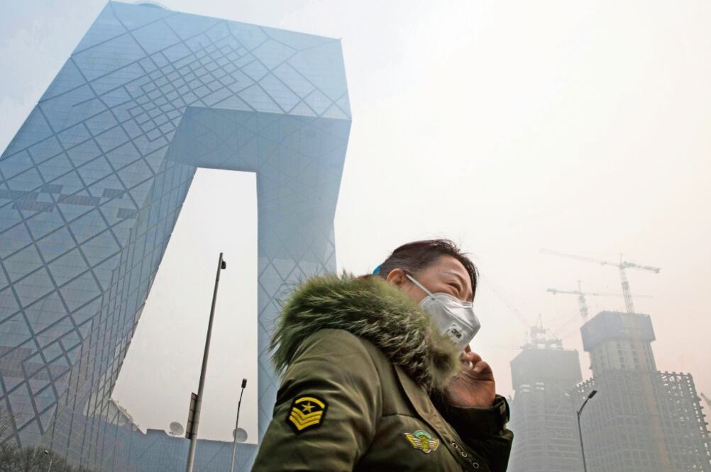 En Asia se registran más muertes por ambientes insalubres, según la OMS. En la foto, una mujer en Beijing, donde se han registrado altos niveles de polución (ARCHIVO AP) 