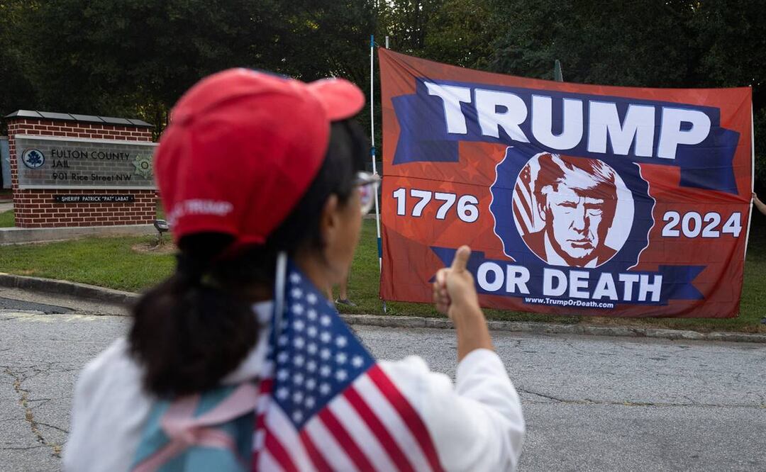 Partidarios del expresidente Donald Trump ondean banderas frente a la cárcel del condado de Fulton previo a su llegada el 24 de agosto. Foto: AFP