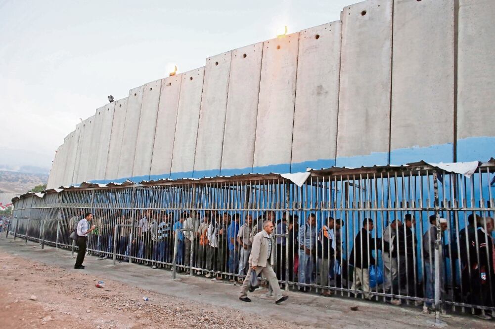 Palestinos esperan para poder cruzar a Jerusalén, de la que los separa un controvertido muro construido por Israel a lo largo de Cisjordania (ARCHIVO. REUTERS)