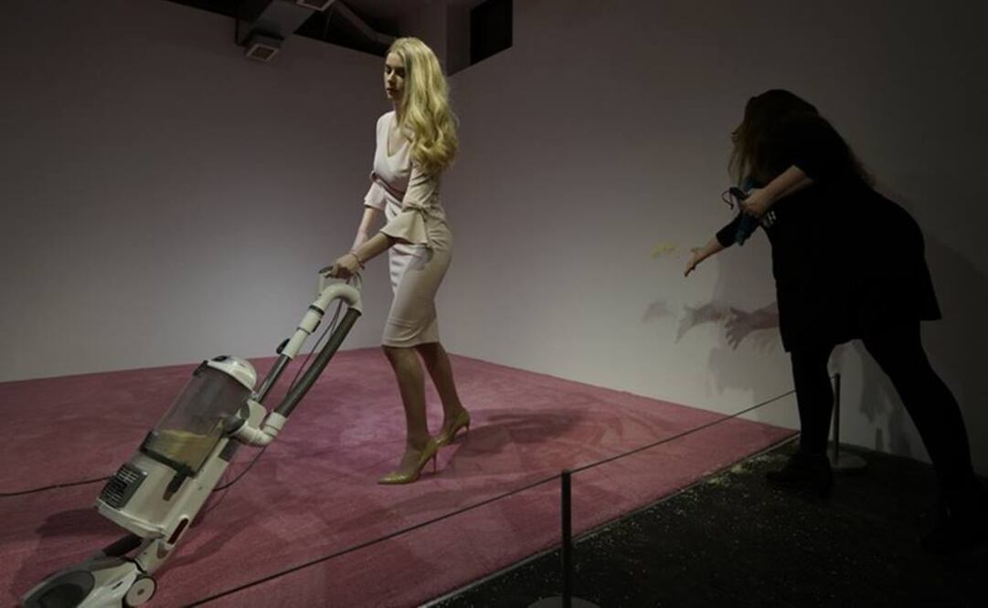 Una espectadora lanza migajas de pan para que una modelo que personifica a Ivanka Trump las aspire en la exposición de arte de Jennifer Rubell titulada “Ivanka aspirando 2019" (Foto. AP)