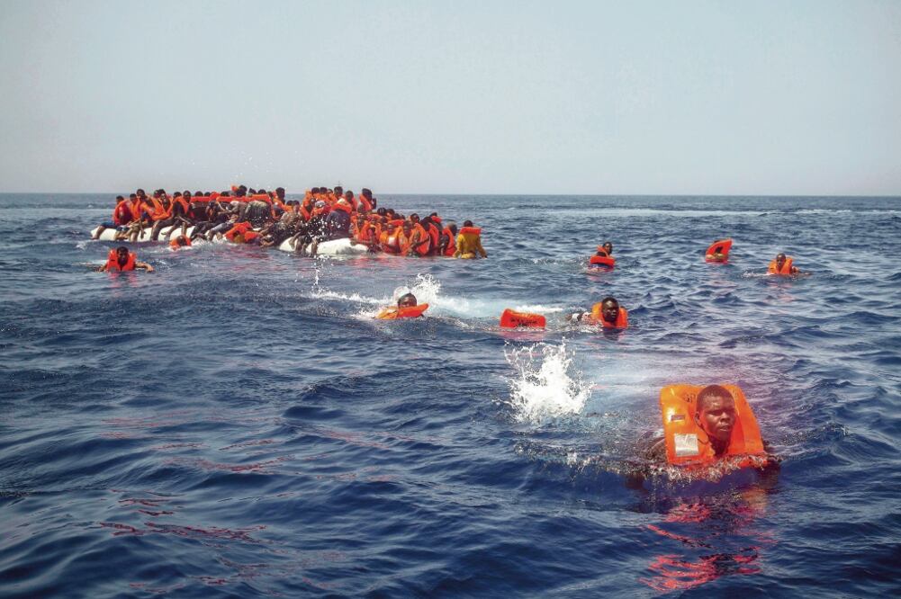 Esta imagen de julio pasado muestra a migrantes africanos intentando llegar a un buque de una ONG desde un bote de goma que naufragó en el Mediterráneo. (SANTI PALACIOS. AP)