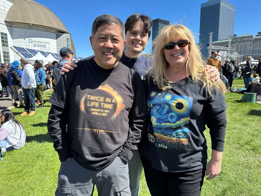 Anthony Tam, con una playera que dice: "Dos veces en la vida", acompañado por su familia, en el Centro de Ciencias de los Grandes Lagos, en Cleveland. Anthony vio el eclipse de 2017 e Casper, Wyoming, y viajó a Cleveland con su esposa Tamara, porque su hijo Joshua estudia en este estado. FOTO: AP