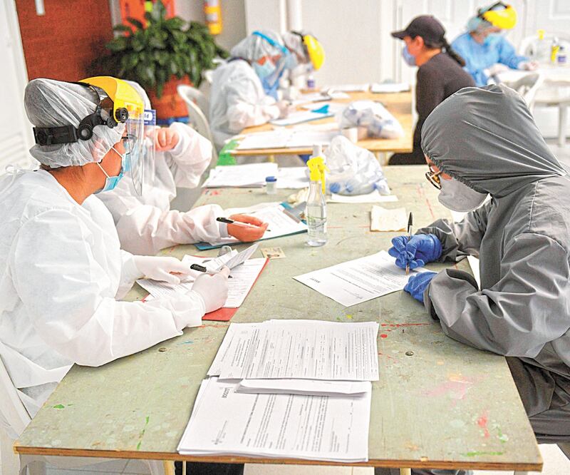 Empleados de salud guardan información mientras realizan pruebas de coronavirus, en un barrio con un alto porcentaje de casos en Bogotá, Colombia. RAUL ARBOLEDA. AFP