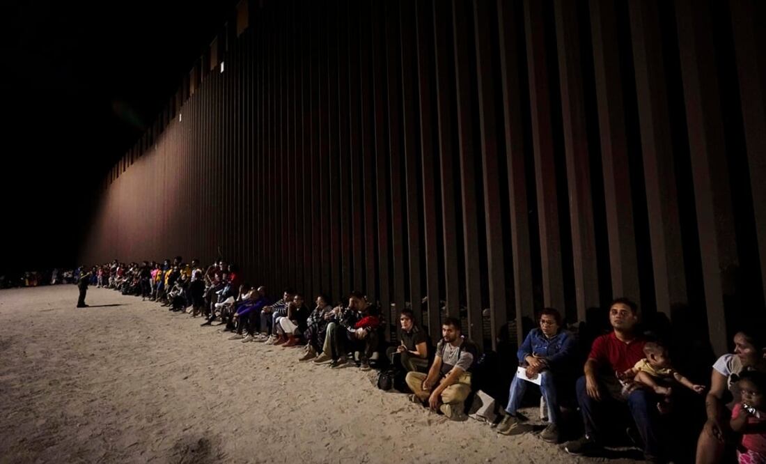 Migrantes junto a un muro fronterizo cerca de Yuma, Arizona, después de cruzar desde México. Foto: AP