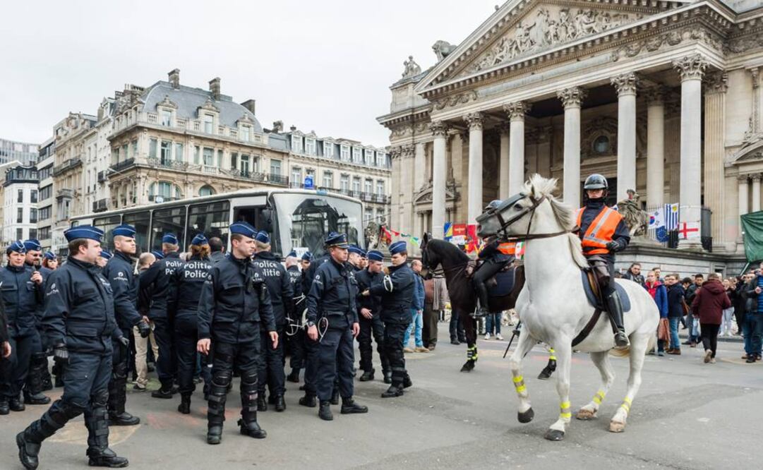 Agentes vigilan la zona alrededor de un autobús policial para el transporte de detenidos en la Place de la Bourse en Bruselas, Bélgica (Foto: AP)
