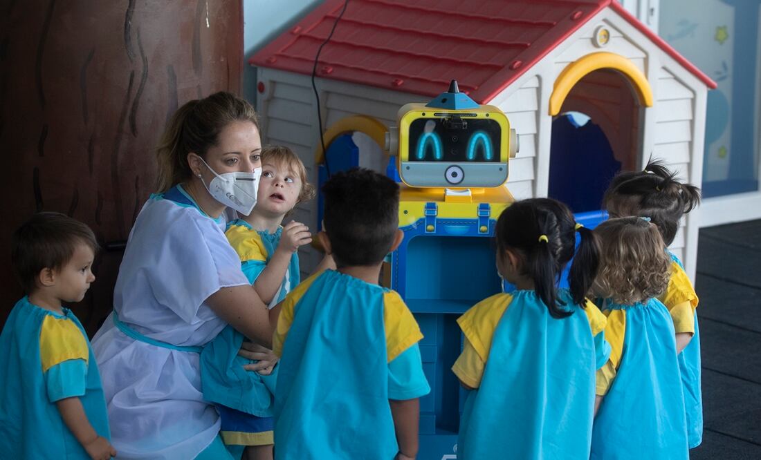 Una maestra les enseña a unos niños un robot que mide la temperatura. Foto: AP /Paul White, archivo