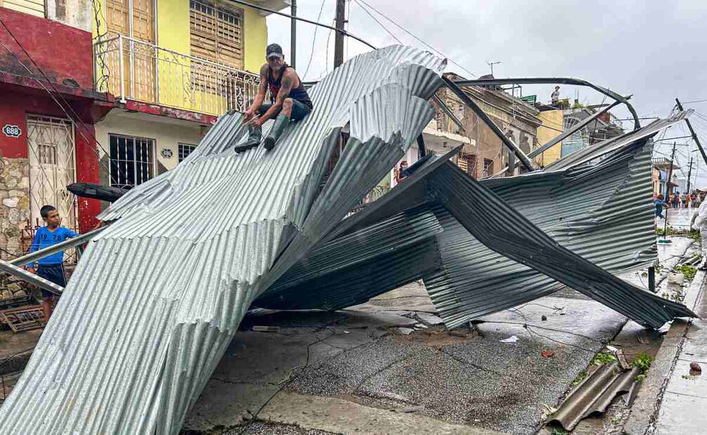 Un residente se sienta en parte del techo de su casa, dañada por el huracán Melissa, en Santiago de Cuba, el 29 de octubre de 2025. Foto: AFP
