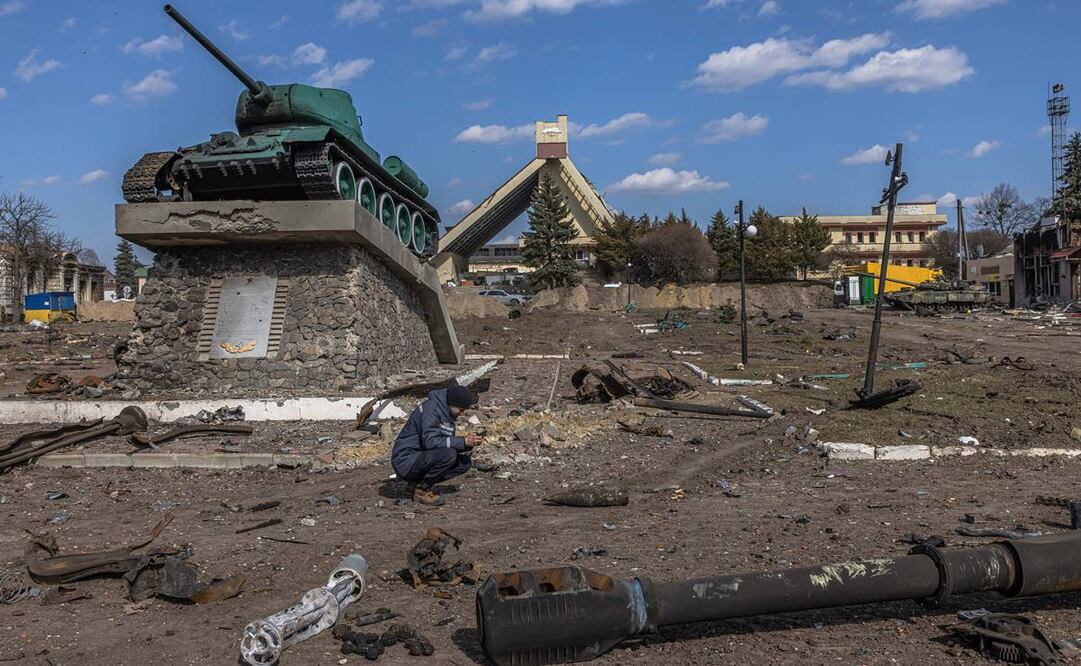 Un rescatista ucraniano examina un objeto explosivo junto a partes de vehículos militares rusos destruidos en el suelo frente a la estación de tren donde estaban estacionadas las fuerzas rusas. Foto: EFE
