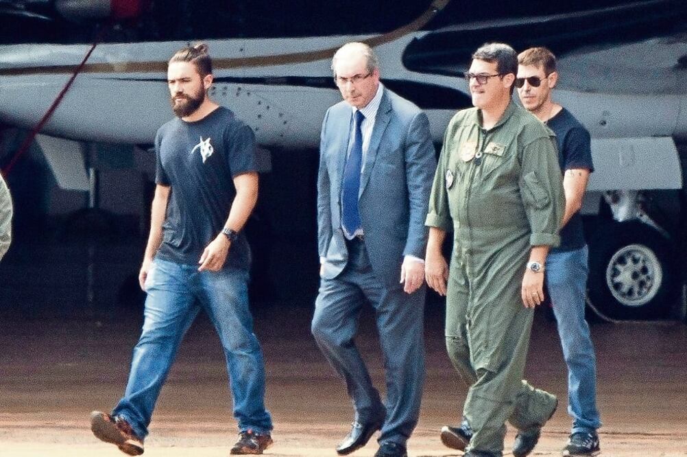 El ex presidente de la Cámara de Diputados de Brasil, Eduardo Cunha (centro), es escoltado en el aeropuerto de Brasilia, para su traslado a Curitiba (MICHAEL MELO. AP)