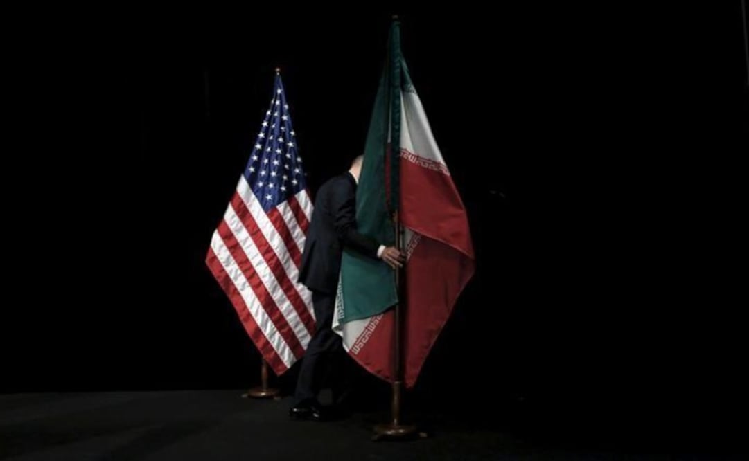 A staff member removes the Iranian flag from the stage after a group picture with foreign ministers and representatives of the U.S. - Photo: Carlos Barria/REUTERS