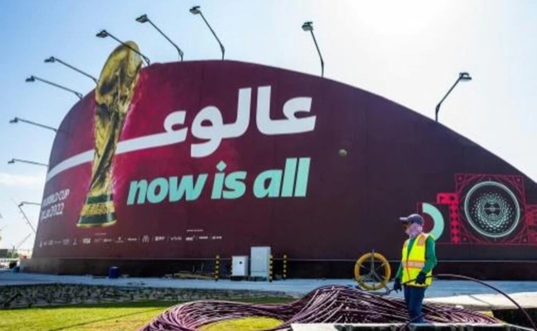 Un hombr trabaja frente a un gran cartel del Mundial de Fútbol de Catar en Doha. Foto: AFP