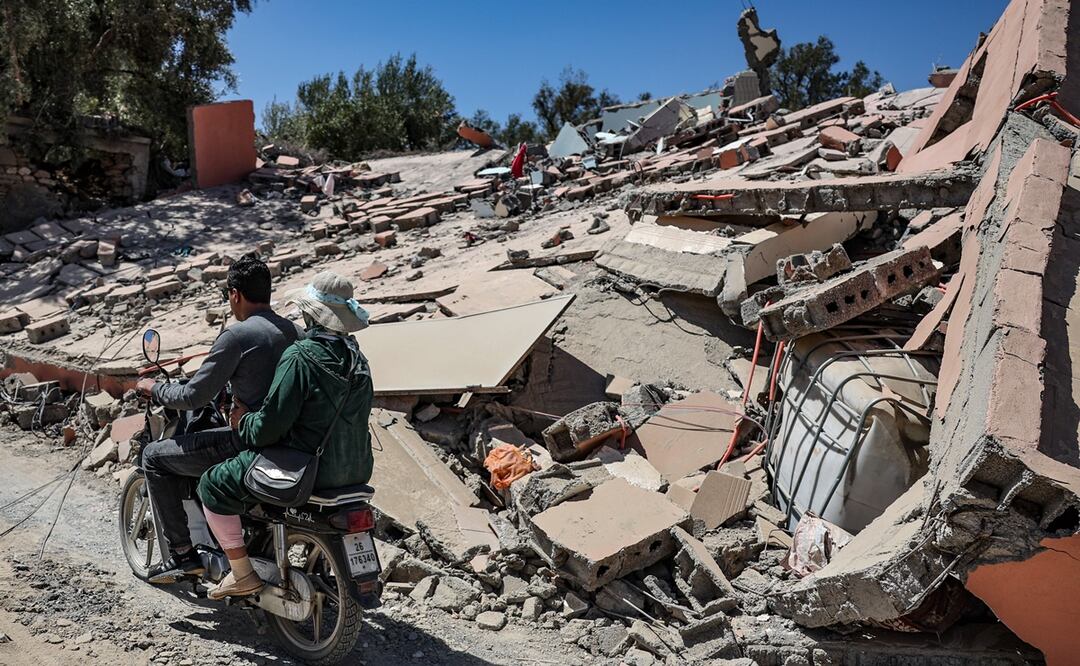Los habitantes pasan en motocicleta por los edificios derrumbados de la aldea de Tafeghaghte, a 60 km al sur de Marrakech, Marruecos. Foto: EFE