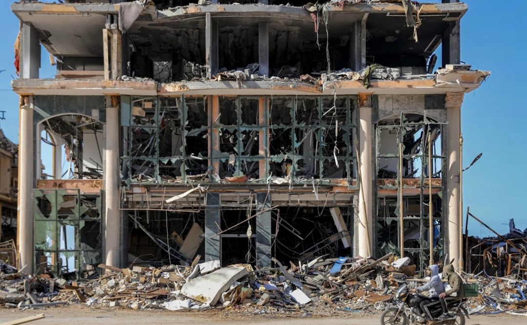 Palestinos pasan en motocicleta junto a un edificio destruido en Ciudad de Gaza el miércoles 29 de noviembre de 2023, en el sexto día del cese el fuego temporal entre Israel y Hamás. Foto: AP