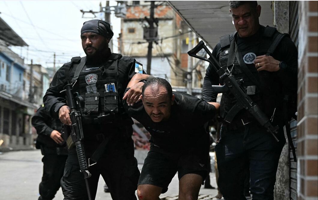 Policías escoltan a un sospechoso arrestados durante la Operación Contención fuera de la favela Vila Cruzeiro, en el complejo Penha, Río de Janeiro, Brasil, el 28 de octubre de 2025. Foto: AFP