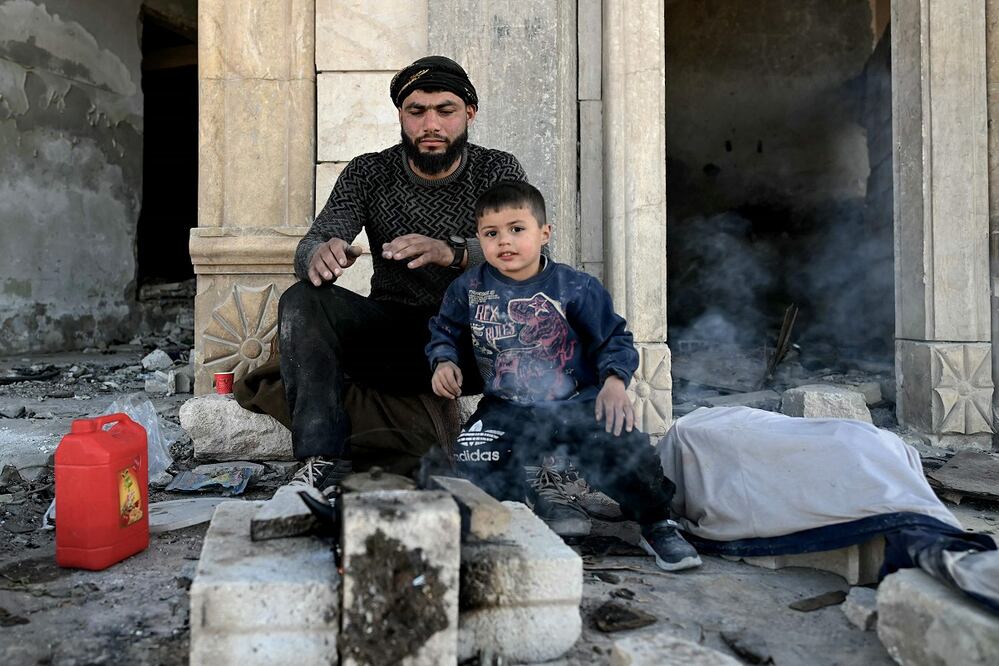 Un hombre descansa con su hijo, tras dedicarse a reparar su casa en Maaret al-Numan, en la provincia siria de Idlib. FOTO: OZAN OSE. AFP