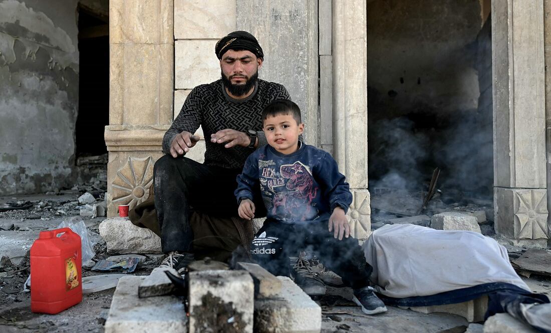 Un hombre descansa con su hijo, tras dedicarse a reparar su casa en Maaret al-Numan, en la provincia siria de Idlib. FOTO: OZAN OSE. AFP