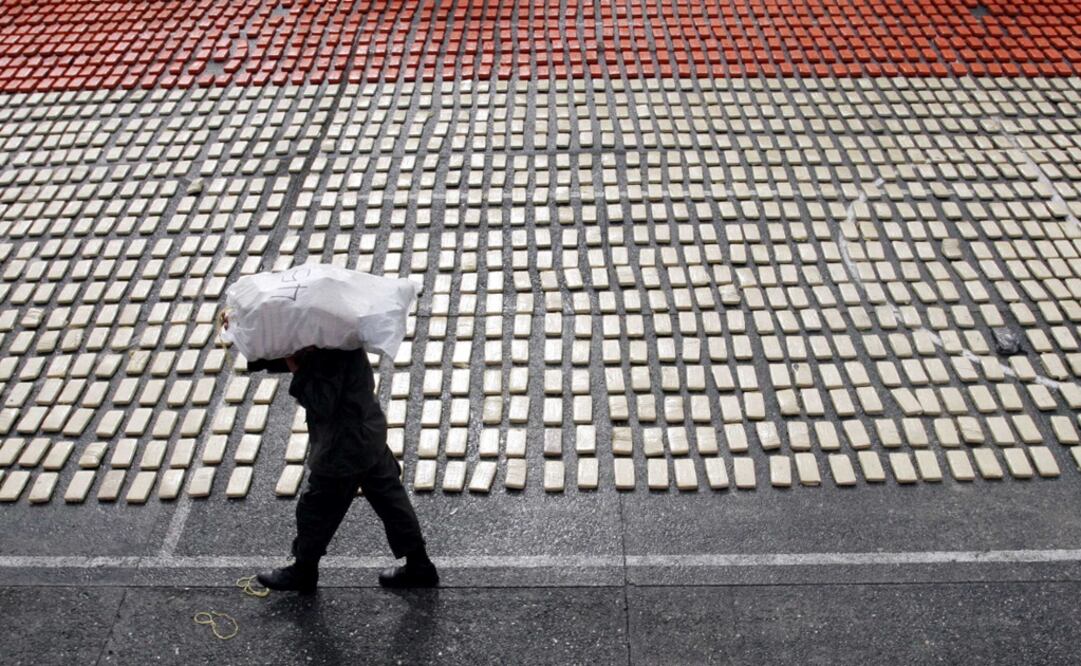 An anti-narcotics police officer carries a sack containing packages of cocaine – Photo: Fernando Vergara/AP