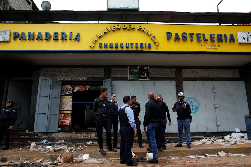Oficiales de policía e investigadores criminales frente a la panadería en Caracas en la que murieron electrocutadas al menos 8 personas (Foto: Reuters)