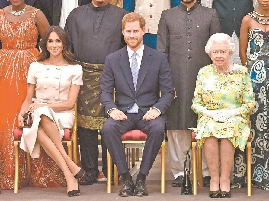 La reina Isabel II (der.) y el príncipe Harry, junto a su esposa Meghan, en un acto en el Palacio de Buckingham. Foto: AFP