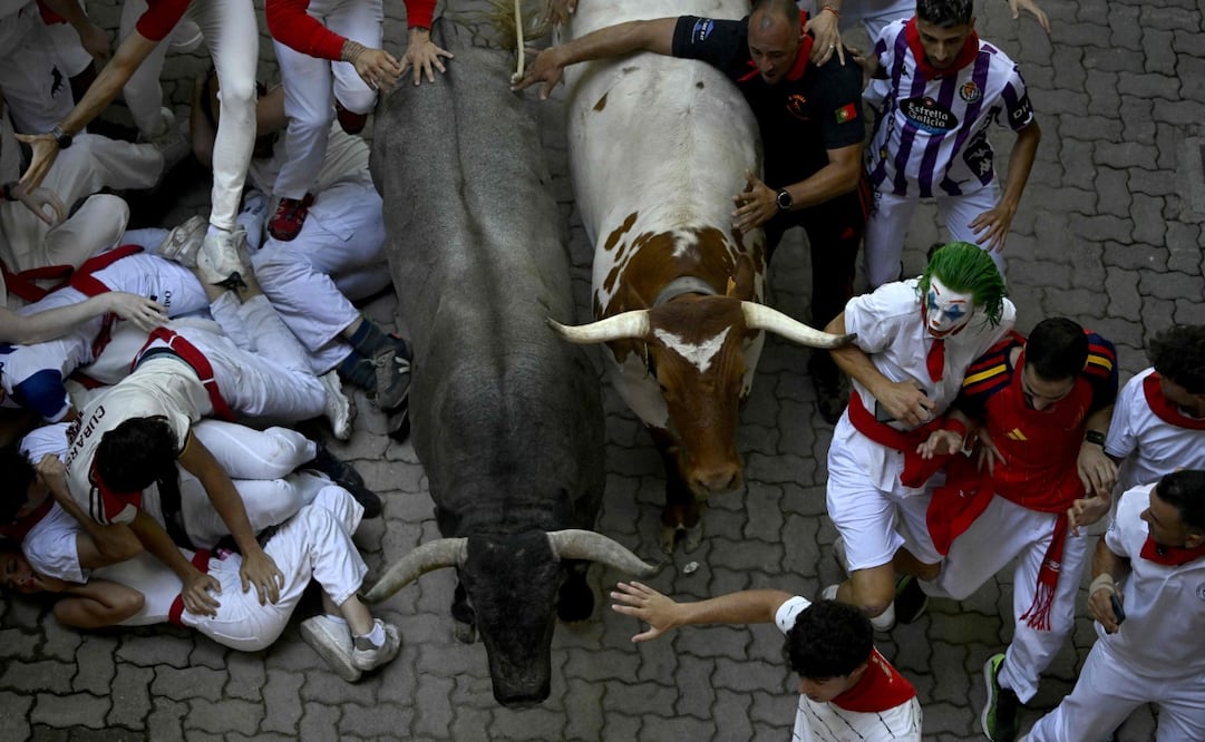 Corredores intentan apartarse mientras los toros avanzan por las calles de Pamplona durante el quinto encierro de las fiestas de San Fermín (11/07/2026). Foto: AFP