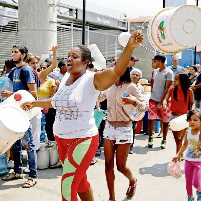 Cientos de vecinos salieron a las calles con cubetas y tambos para buscar agua, ante la falta del recurso en algunas zonas de Caracas, capital del país. Algunos aprovecharon los chorros que se derramaban de un puente. CARLOS GARCIA. REUTERS
