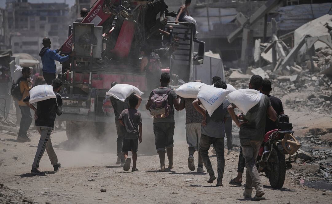 Palestinos llevan sacos de harina descargados de un convoy de ayuda humanitaria que llegó a la ciudad de Gaza desde el norte de la Franja de Gaza. Foto: AP