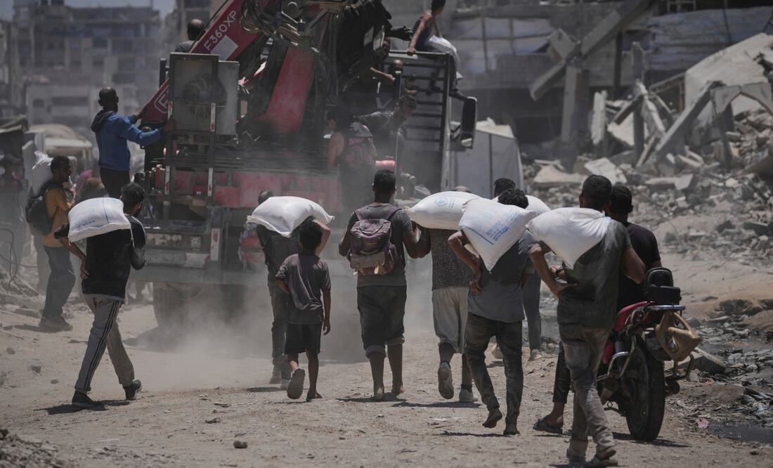 Palestinos llevan sacos de harina descargados de un convoy de ayuda humanitaria que llegó a la ciudad de Gaza desde el norte de la Franja de Gaza. Foto: AP