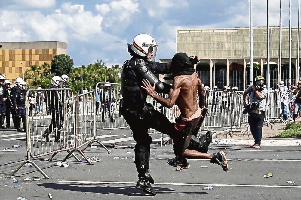 Un policía pelea con un manifestante, en la Explanada de los Ministerios, en Brasilia, donde se cometieron actos de vandalismo en las sedes de Agricultura, Cultura, Planeación y Medio Ambiente (FERNANDO BIZERRA JR. EFE)