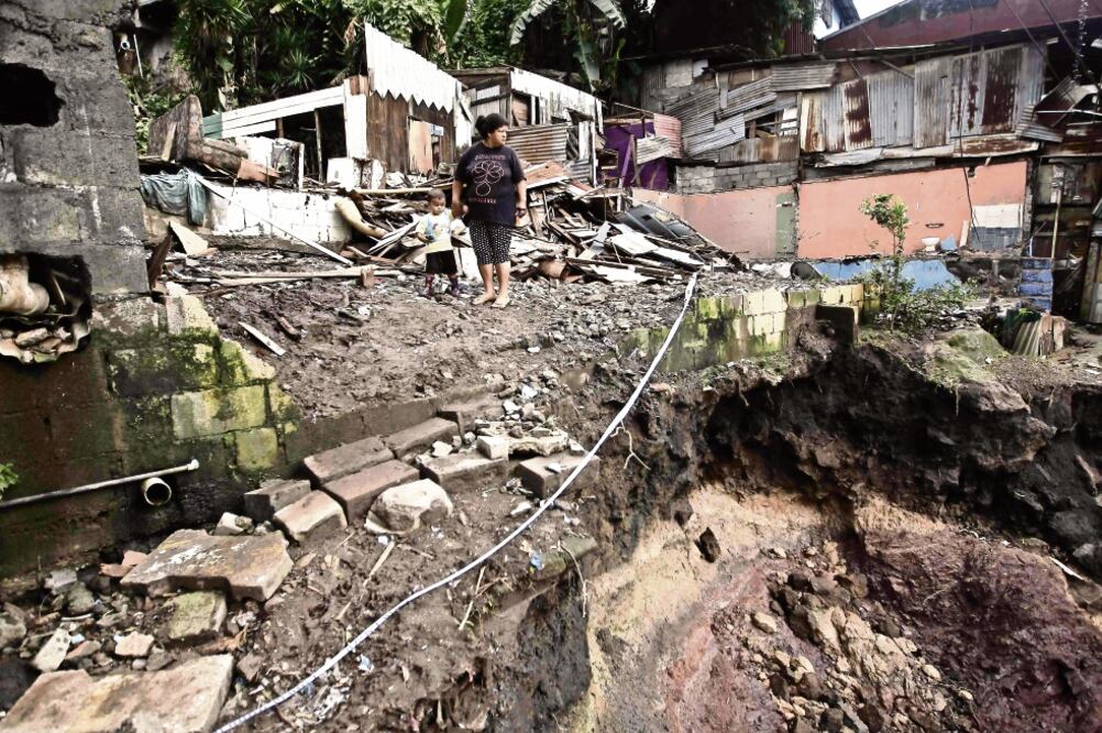 Una mujer con un niño tomado de la mano observa los daños ocasionados por la tormenta tropical Nate , que destruyó casas en la localidad del Barrio Los Anonos, al oeste de San José, Costa Rica. (JEFFREY ARGUEDAS. EFE)