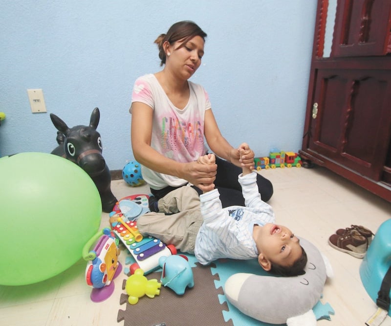 Mientras ejercita las piernas de Edson, Carolina recuerda que en su séptimo mes de embarazo los médicos le dijeron que el perímetro de la cabeza de su hijo era más pequeño de lo que debía ser, que tenía microcefalia por posible zika. Fotos: CARLOS MEJÍA