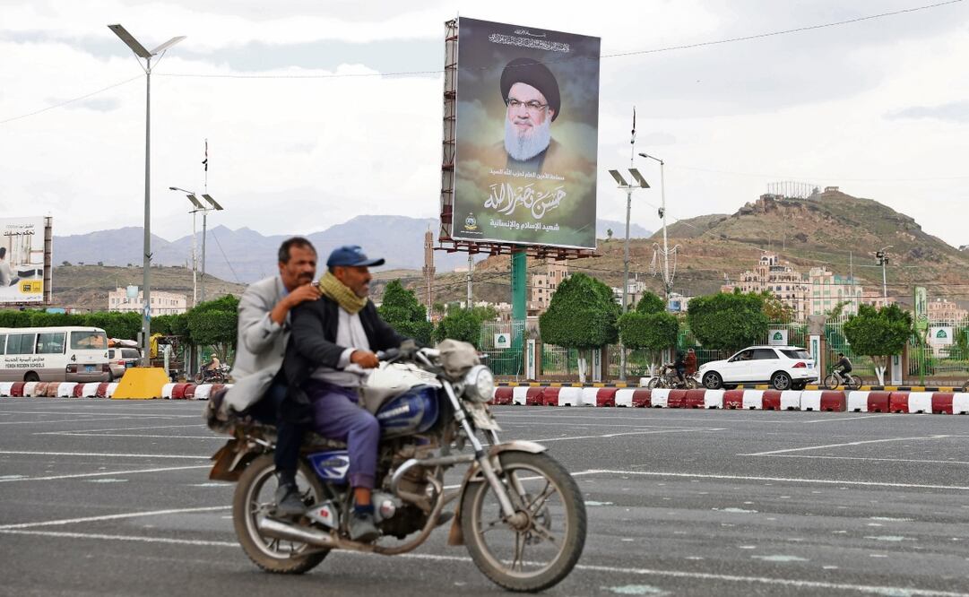 Dos personas pasan frente a un retrato del fallecido Hassan Nasralá, en Saná, la capital de Yemen. El líder de Hezbolá murió en un ataque israelí el pasado 28 de septiembre Foto: EFE