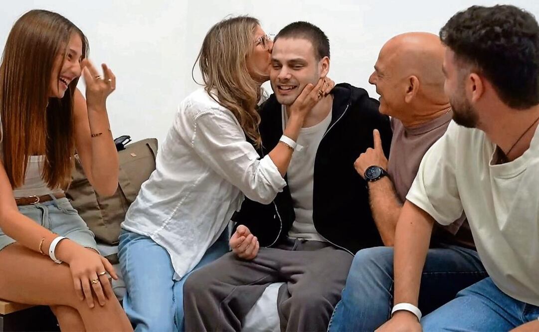 Alon Ohel recibe un beso de su madre, mientras su familia expresa la alegría de volver a verlo tras dos años de cautiverio. Foto: AFP