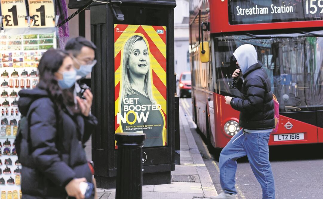 Peatones pasan junto a un anuncio que promueve el programa de refuerzo de la vacuna contra el coronavirus del Servicio Nacional de Salud de Reino Unido, en el centro de Londres. Foto: Tolga Akmen. AFP