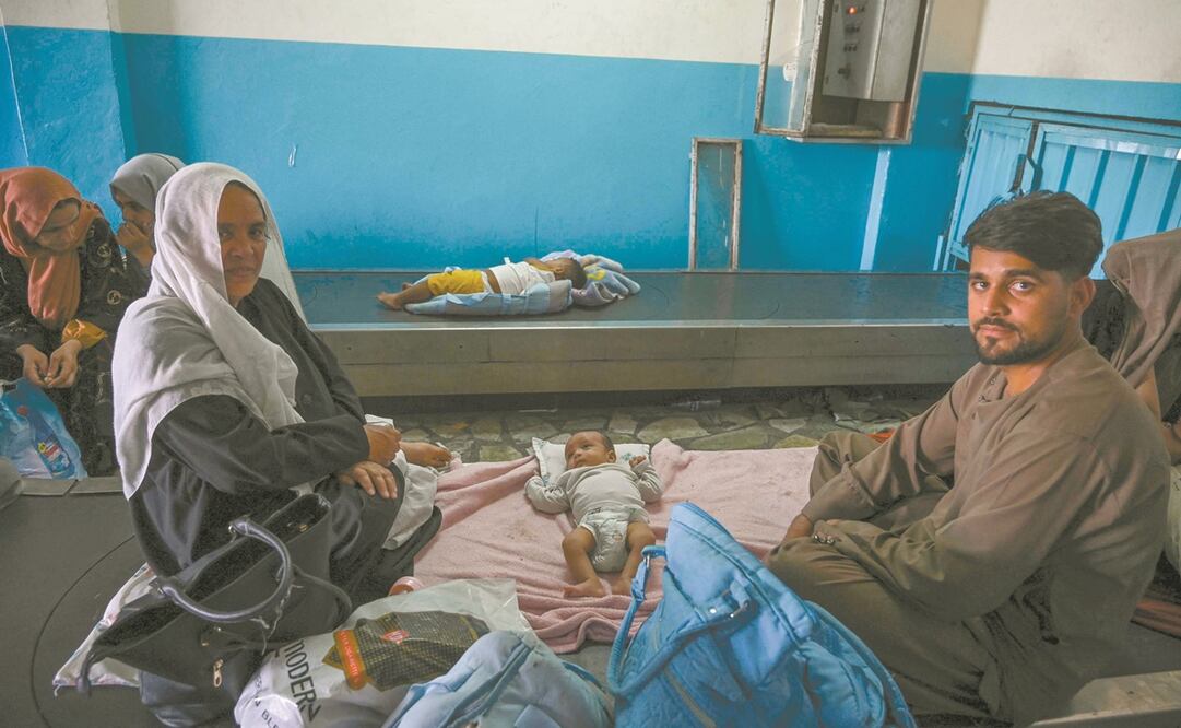 Familias afganas esperan en el área de equipaje, en el aeropuerto de Kabul. Foto: Wakil Kohsar. AFP