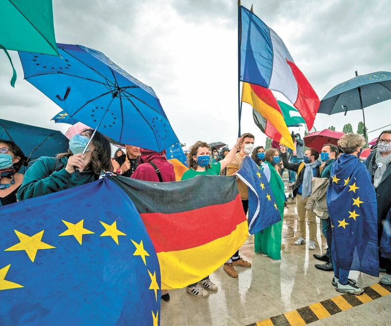 Personas con banderas se reunieron ayer en el cruce peatonal Dos Bancos, en vísperas de la reapertura de las fronteras entre Francia y Alemania. Foto: PATRICK HERTZOG. AFP