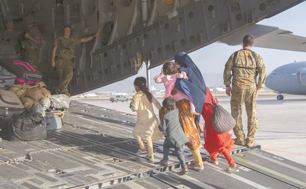 Pilotos y capitanes de la Fuerza Aérea estadounidense, con personas evacuadas en el Aeropuerto Internacional Hamid Karzai, en Kabul. Foto: AP.