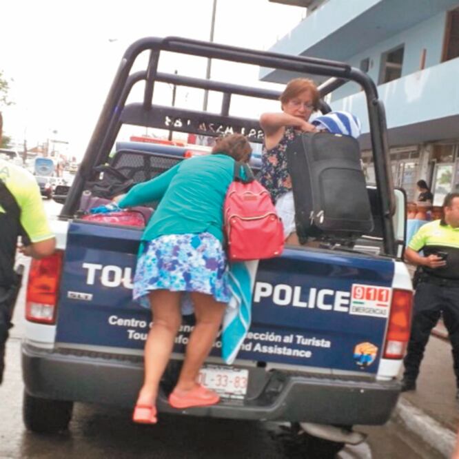 Elementos de la Policía Turística auxiliaron a una familia que quedó aislada con maletas en el centro de Mazatlán debido a la inundación. CORTESÍA