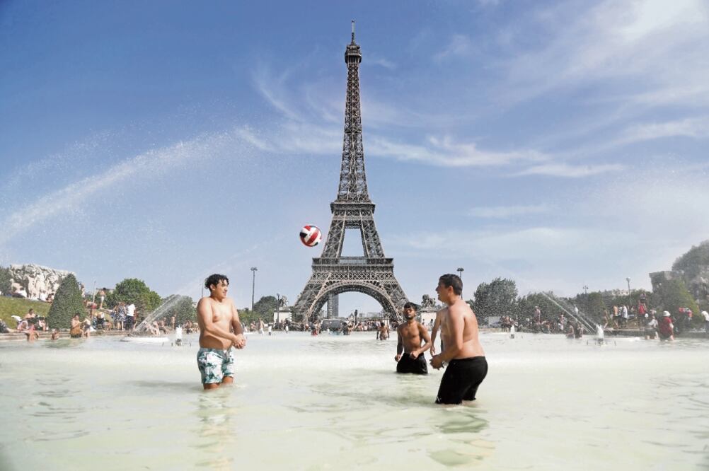 En los lugares cercanos a la Torre Eiffel, parisinos se refrescaron ayer en un día en el que se registraron 45 grados. Foto: AFP