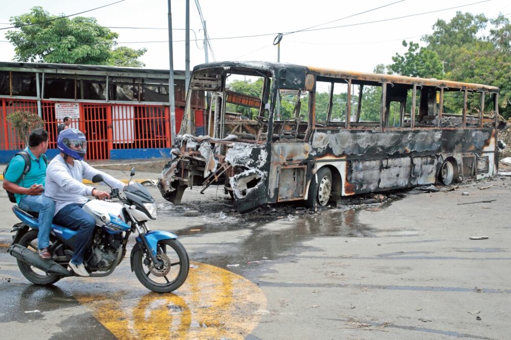 Dos motociclistas pasan por donde está un autobús que fue quemado durante las protestas en Nicaragua contra el gobierno de Daniel Ortega, en Managua. Las protestas han dejado 200 muertos, según una ONG (OSWALDO RIVAS. REUTERS)