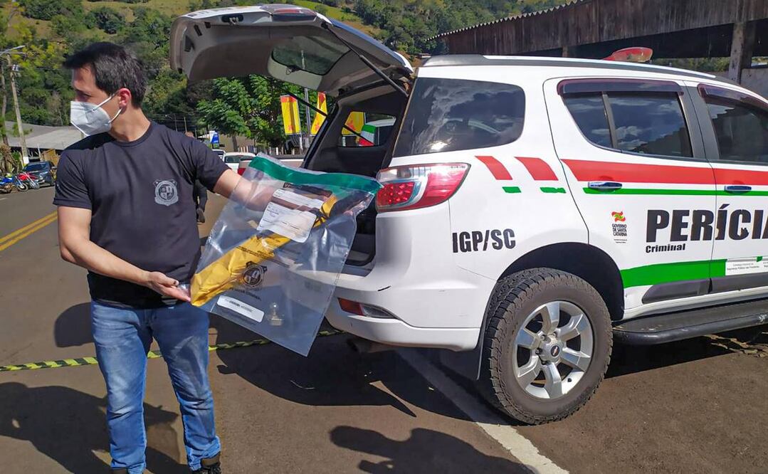 Un investigador criminalístico carga hoy como evidencia el machete que usó un joven para matar a 5 personas en una guardería de Saudades, Brasil. Foto: EFE