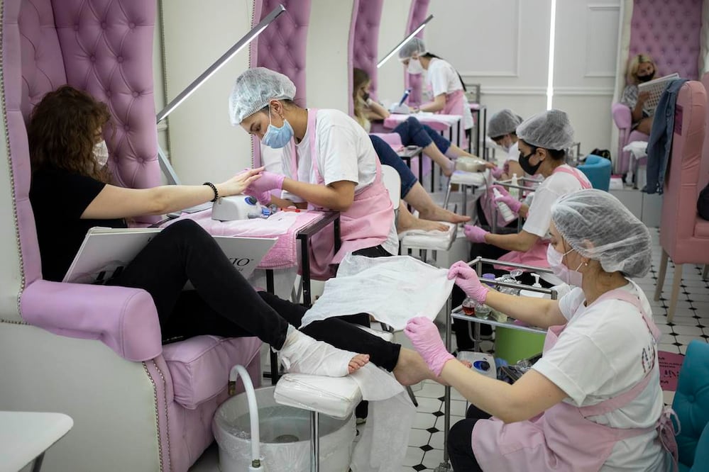 Personal de un salón de belleza porta mascarillas y guantes para atender a sus clientes en Moscú, Rusia, el martes 9 de junio de 2020. (AP Foto/Pavel Golovkin)