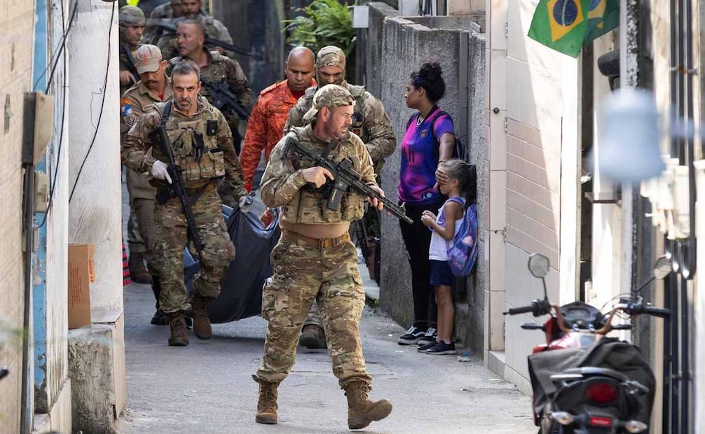 Antes de que ella vea
Una mujer cubre el rostro de un niño mientras la policía pasa con el cuerpo de un sospechoso asesinado en un operativo en Ladeira dos Tabajaras. La imagen simboliza la violencia urbana en Río de Janeiro. Foto: Márcia Foletto / O Globo, Brasil