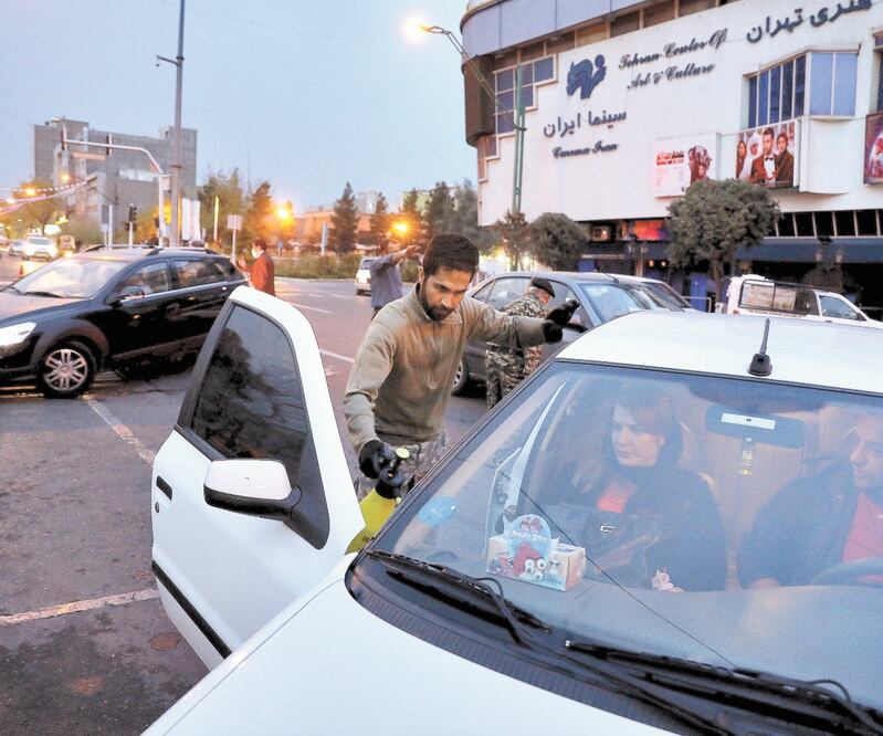 Elementos de la Guardia Revolucionaria de Irán desinfectan automóviles, en Teherán, para ayudar a prevenir que se expanda más el coronavirus. EBRAHIM NOROOZI. AP