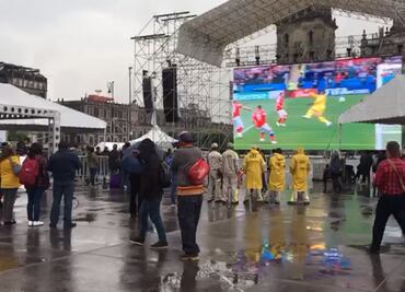Bajo la lluvia, capitalinos acuden a transmisión del Mundial en el Zócalo