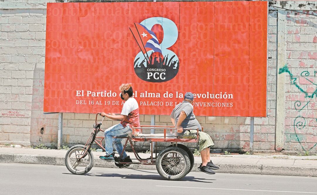 Cubanos, frente a una valla que promociona el VIII Congreso del Partido Comunista de Cuba (PCC), en La Habana. Foto: Ernesto Mastrascusa. EFE