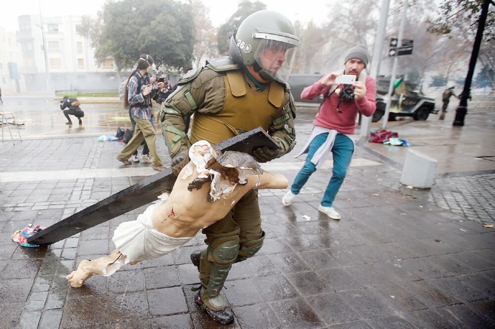 Policías rescatan el crucifijo de la Iglesia de la Gratitud Nacional, extraí do por jóvenes durante la protesta de ayer en Santiago de Chile (MARIO RUIZ. EFE)